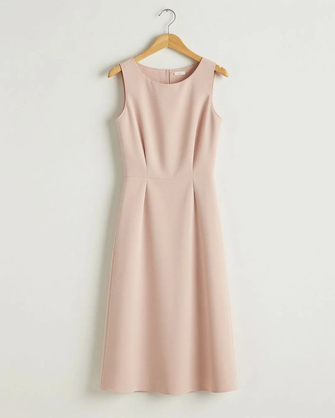 Blush midi dress on a wooden hanger in a studio
